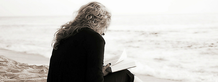 Die Lust am Lesen wieder neu entdecken Eine Frau sitzt am Meer und liest ein Buch